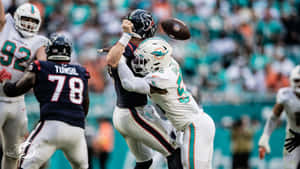 NFL美式足球員在日間比賽中被空中擒抱，背景有觀眾。