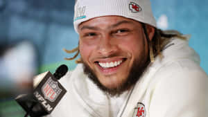 NFL球員在記者會上戴著酋長隊冷帽和連帽衛衣微笑。