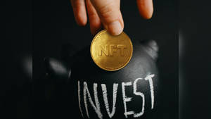 手將NFT硬幣放入標有invest的豬仔錢罌