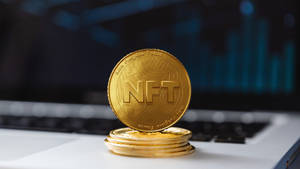 筆記型電腦鍵盤上的金色NFT硬幣，金融圖表背景。