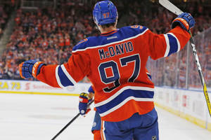 冰球運動員 Connor McDavid 在冰上高舉雙臂慶祝勝利。 — 冰球 壁紙