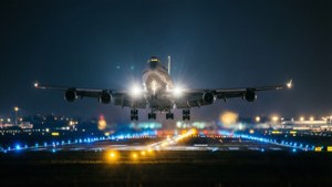夜間大型飛機降落，跑道上有明亮燈光