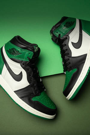 黑色、白色和綠色的Jordan 1波鞋在綠色背景上。