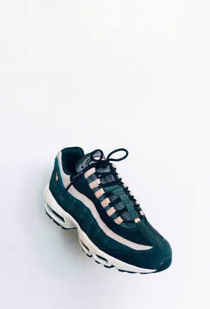 白色背景上帶有蜜桃色條紋和白色鞋底的黑色Nike Air Max 95運動鞋。