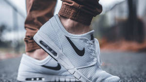 白色Nike運動鞋，帶有黑色swoosh標誌，在瀝青路面上。