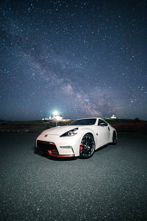 白色跑車停放在星空下，銀河可見。