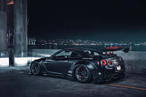 黑色改裝日產GT-R夜晚停泊，背景係城市燈光。