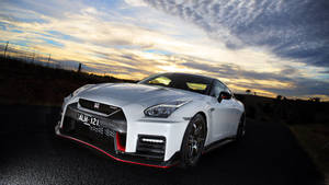 白色日產GT-R跑車帶紅色飾邊，停在日落時分的道路上。