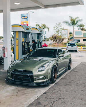 陰天下，加油站內的橄欖綠色日產GT-R配金色輪圈。 — 汽車 壁紙