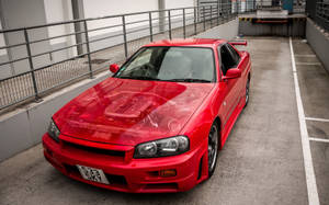 紅色日產Skyline R34停放在混凝土停車場。 — 天際線 壁紙