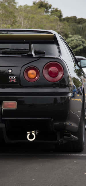 黑色日產GT-R跑車停泊，後面有樹木。