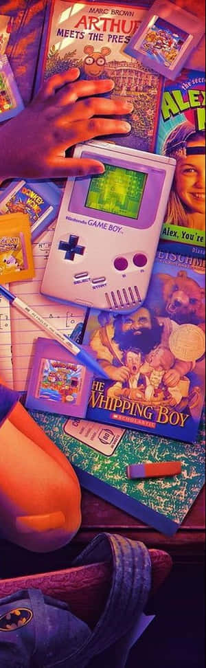 孩子的手拿著紫色 Game Boy，周圍有書籍和學校用品。