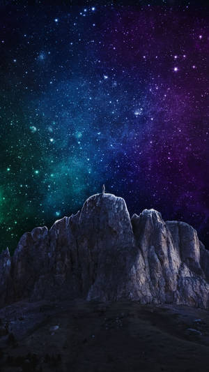 一個人在岩石山峰上的剪影，背景是色彩繽紛的星空。
