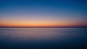 黃昏時平靜的海洋，天空從藍色漸變到橙色