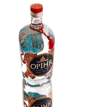 Opihr氈酒瓶，紅色瓶蓋和藍色標籤，在白色表面上反射。