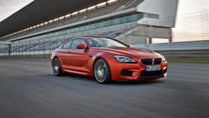 橙色BMW M6在賽道上高速行駛，背景為看台。 — 平治 C300 壁紙