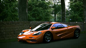 橙色McLaren F1超級跑車停放在森林環境中的乾草捆附近。 — 4K 法拉利 壁紙
