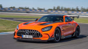 橙色Mercedes-AMG GT R在日落時分的賽道上疾馳。 — 平治 AMG 壁紙