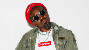 男士戴紅色冷帽太陽眼鏡Supreme T恤綠色外套在白色背景前擺姿勢