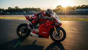 紅色Ducati電單車在賽道上奔馳，車手在日落時入彎傾斜