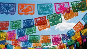 色彩繽紛的 papel picado 橫幅掛在藍天白雲前
