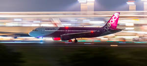 Peach Airlines 飛機在夜間快速移動在跑道上，燈光模糊。