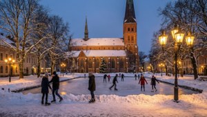 溜冰者在黃昏時分在歷史悠久的教堂附近的雪地溜冰場上滑行。