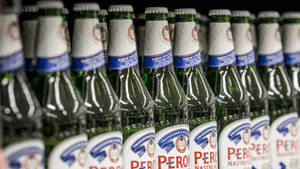 一排排帶有白色和藍色標籤的綠色 Peroni 啤酒瓶。
