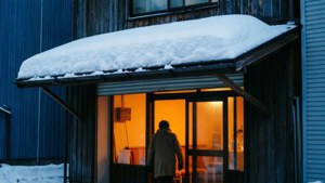 冬天，一個人喺被雪覆蓋嘅簷篷下進入溫暖明亮嘅建築物。