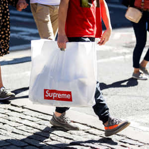 在鵝卵石街道上行走的人拿著 Supreme 購物袋。