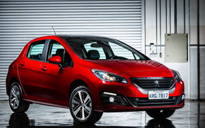 紅色Peugeot 208停放在乾淨的工業車庫中，地板具有反射效果。