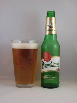 綠色Pilsner Urquell啤酒樽旁邊有一杯滿嘅啤酒，有泡。