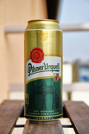 戶外木桌上的金色Pilsner Urquell啤酒罐。