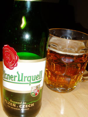 夜晚木枱上嘅綠色啤酒樽同加冰啤酒杯。