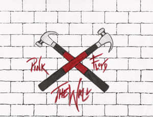 白色磚牆上兩把交叉的紅色手柄錘子，帶有Pink Floyd The Wall塗鴉。