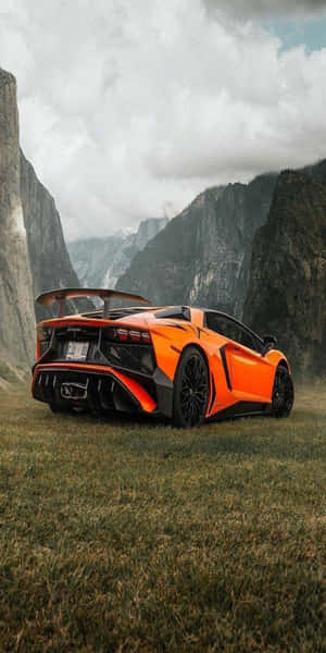 橙色林寶堅尼 Aventador 停泊在陰天下岩石懸崖附近的草地上。 — 蘭博基尼 壁紙
