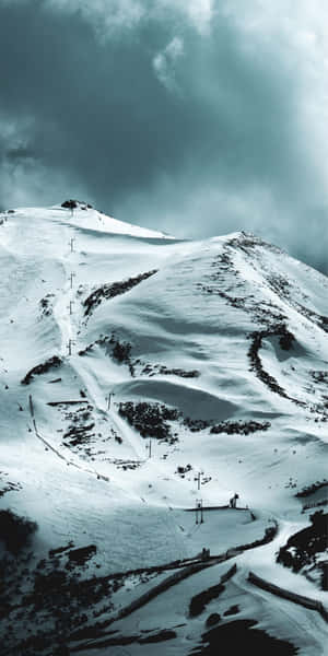 黑暗風暴雲下，雪覆蓋的山，設有滑雪纜車和小徑。