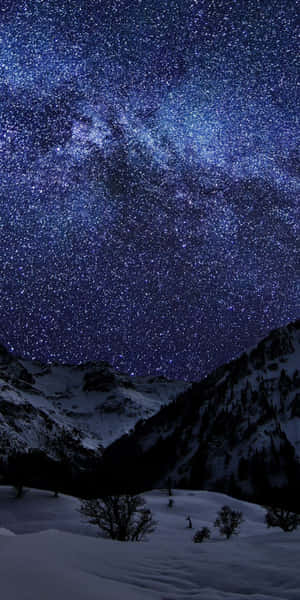 在繁星點點的夜空下，積雪的山峰和可見的銀河。
