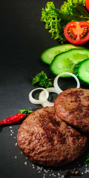 兩塊烤牛肉漢堡扒配新鮮蔬菜放在深色石板上。 — Pixel 3 壁紙