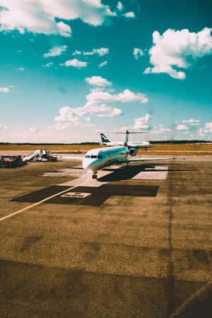 一架商用飛機停在機場停機坪上，天空湛藍，白雲點綴。