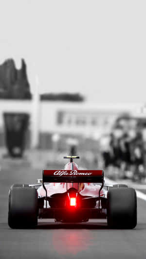 紅色愛快羅密歐F1賽車在賽道上疾馳，尾燈發光。