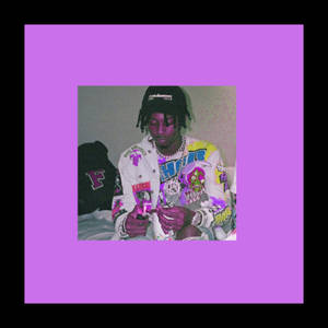年輕男子身穿圖案外套和鏈條坐在床上手持小物件 — Playboi carti GIF 壁紙