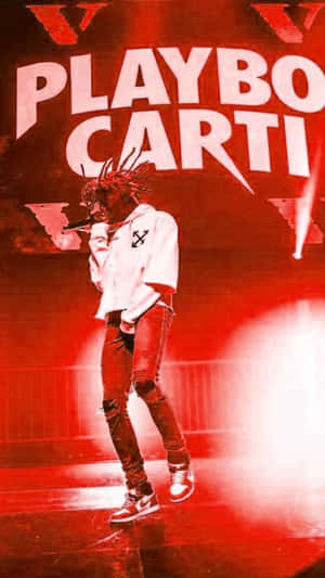 說唱歌手 Playboi Carti 在紅色舞台上表演，身穿白色連帽衫和破洞牛仔褲。