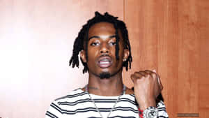 留辮子頭的男子身穿條紋襯衫和手錶，靠著木牆擺姿勢。 — Playboi carti GIF 壁紙