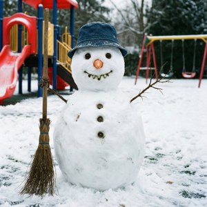 雪人戴著牛仔帽在雪地遊樂場拿著掃帚