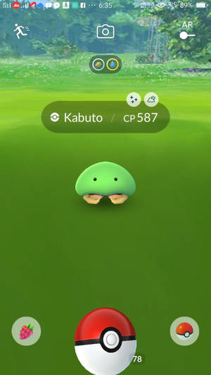一隻綠色的 Kabuto 寶可夢在 Pokémon GO 遊戲介面中的草地上。
