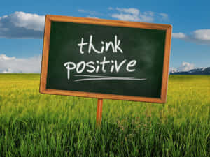 草地入面嘅黑板，藍天下有 think positive 訊息