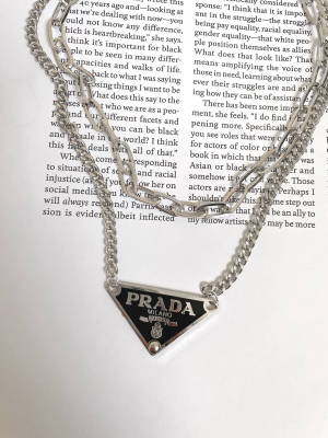 銀色 Prada 項鍊放在印有文字的打開書頁上