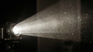 一部電影放映機在黑暗的房間中發出一道明亮的光束穿過飄浮的灰塵。