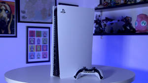 白色PlayStation 5主機和手掣在桌上，配有藍色燈光和普普藝術海報。